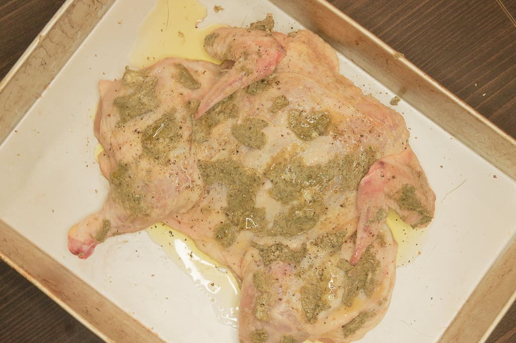 Picture of whole raw chicken covered in herb butter and olive oil