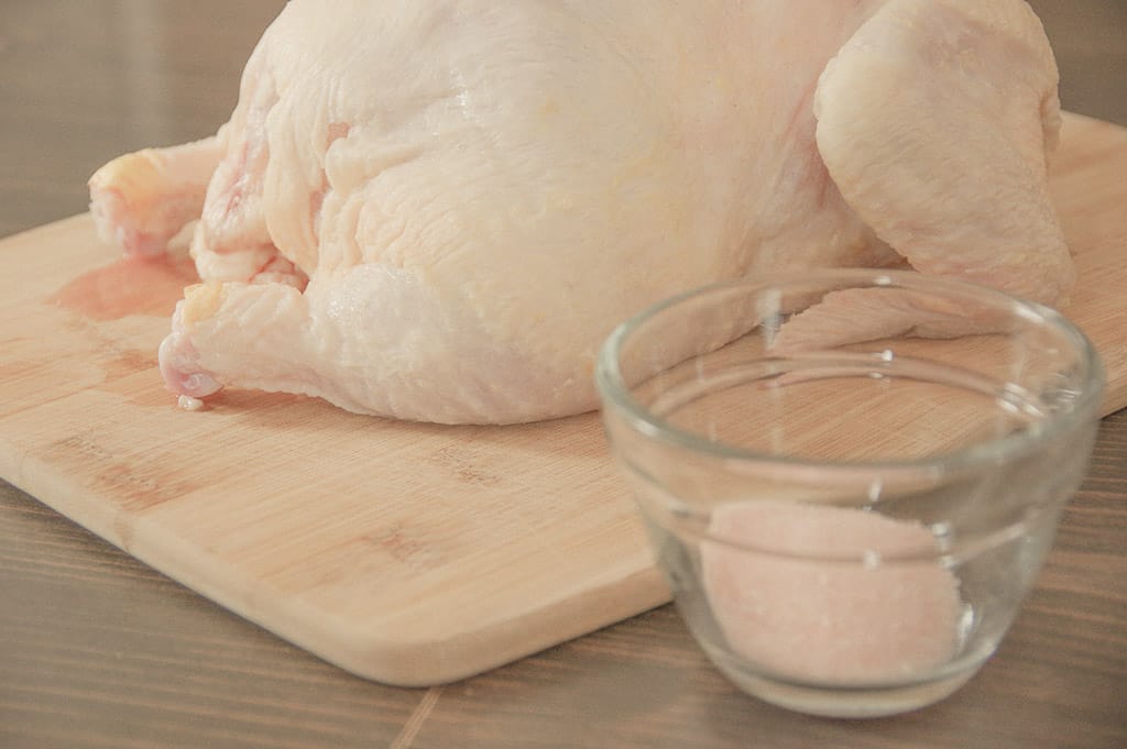 Close-up of raw chicken on a cutting board and salt in a bowl