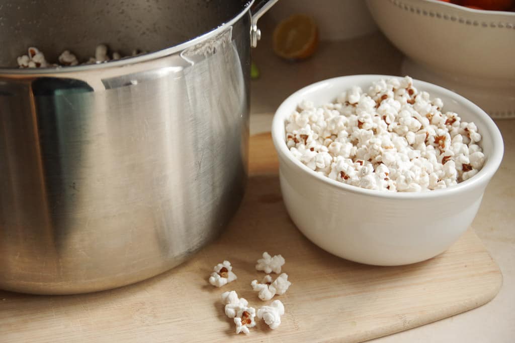 Pop corn in a bowl next to a large pot with popcorn