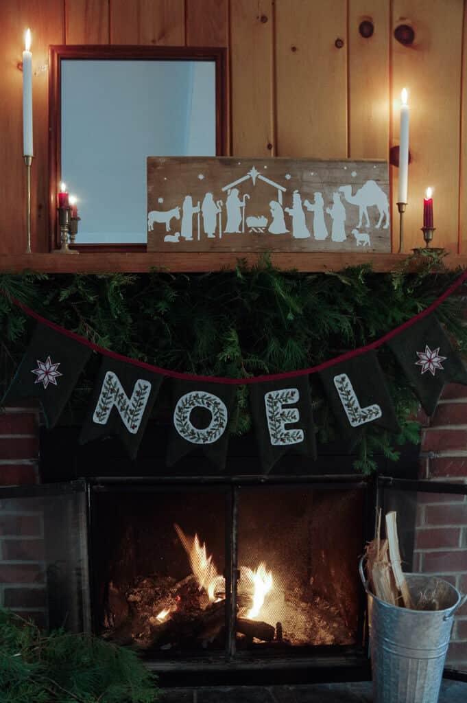 Mantel with fabric banner, pine garland and a fire