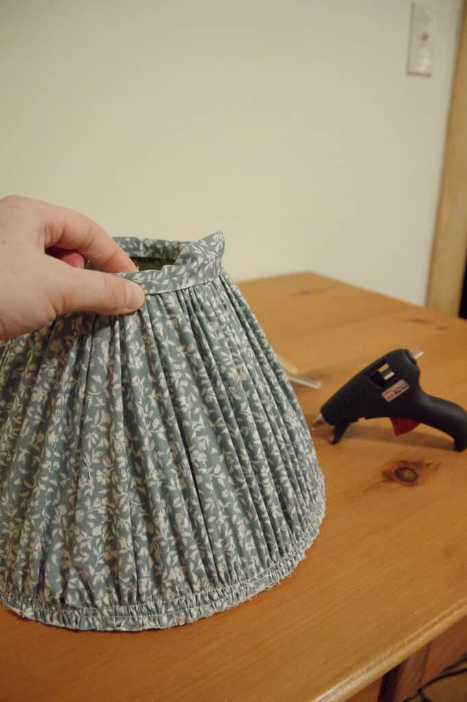 Hand holding top edge of lampshade