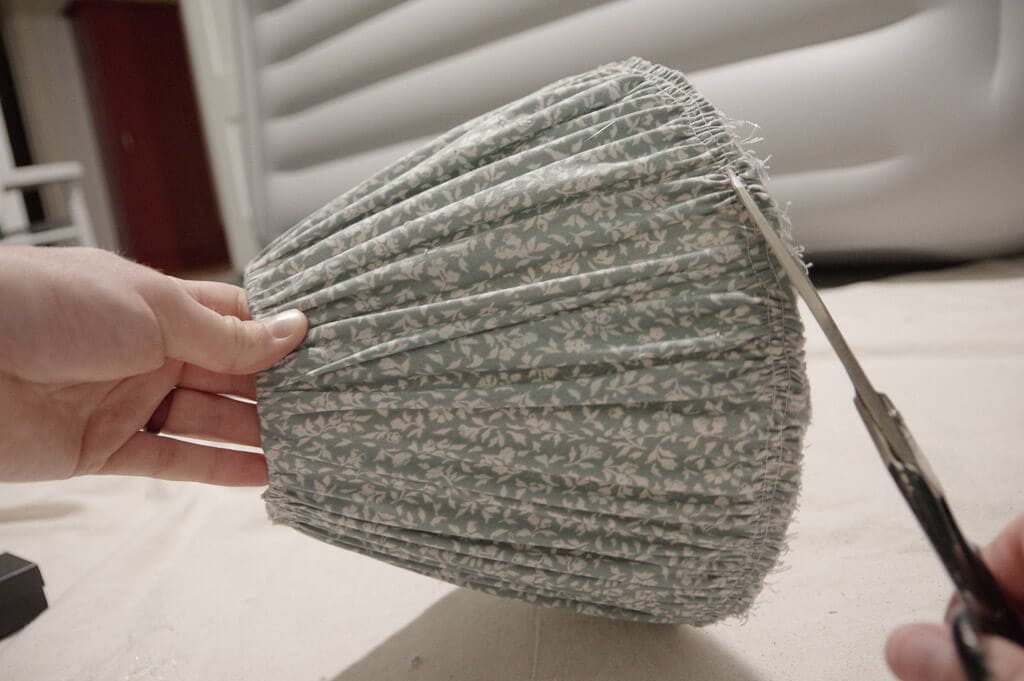 Scissors trimming frayed fabric on lampshade