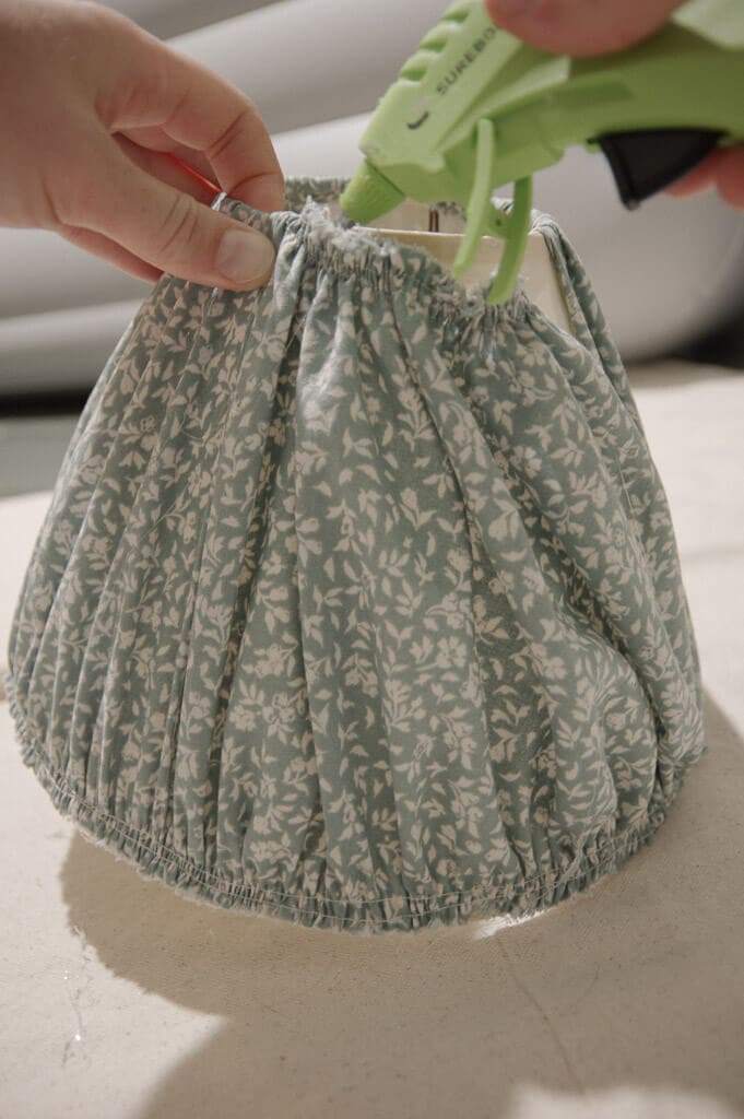 Hands gluing fabric onto lampshade