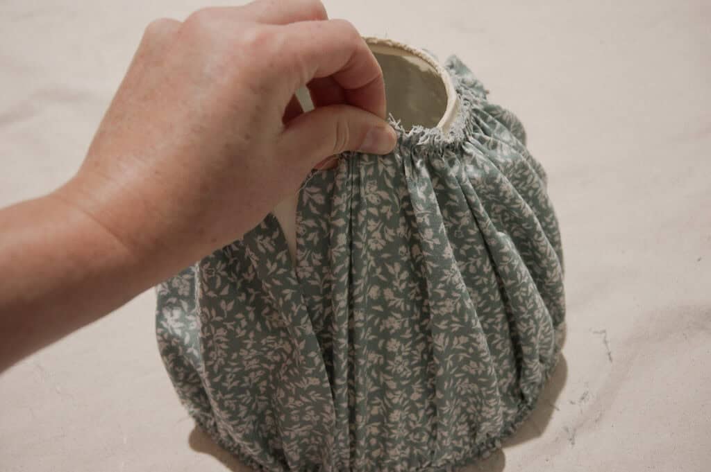 Hand pulling fabric on lampshade