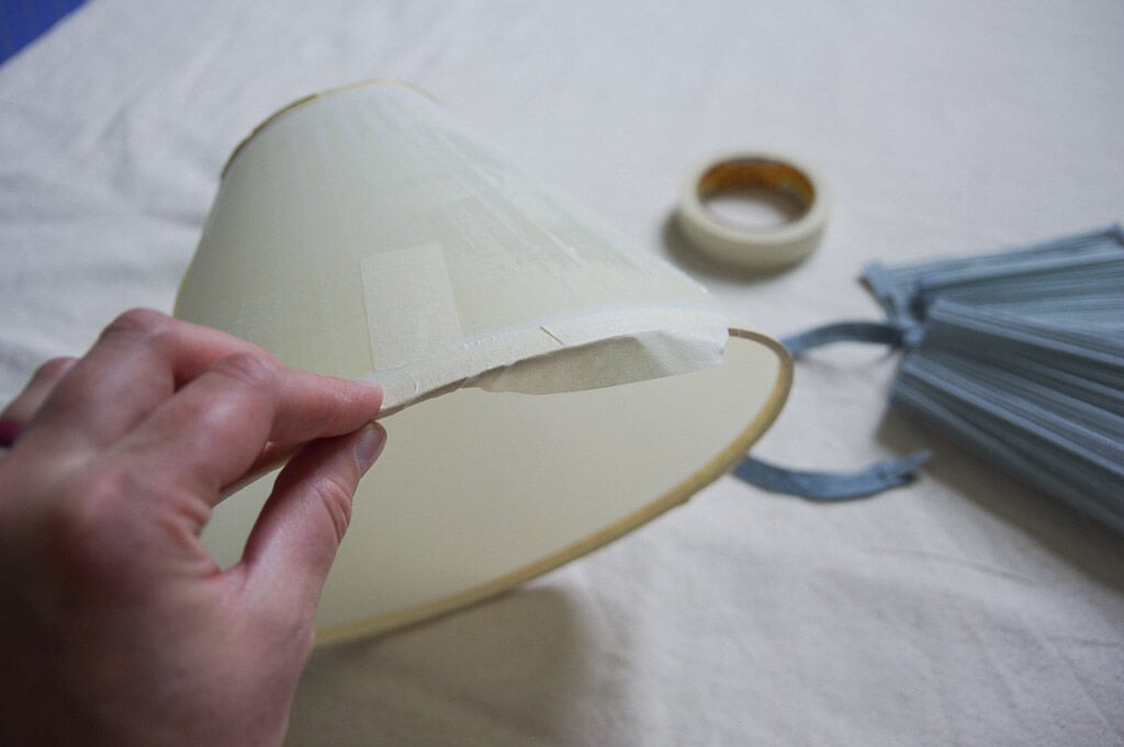 hand holding lampshade with tape on edge