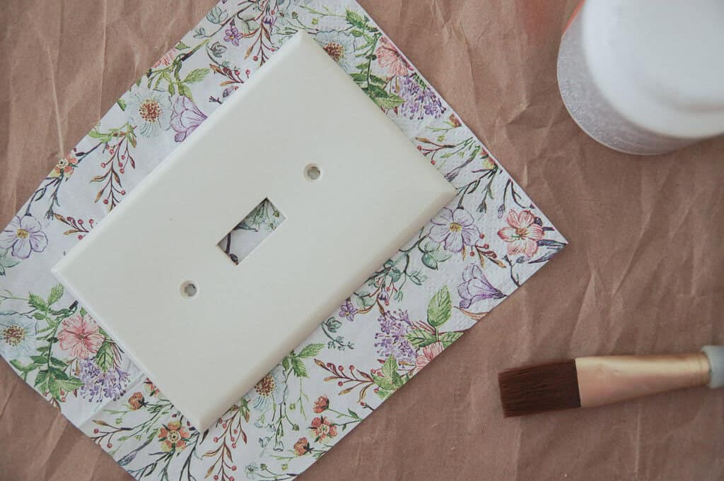 Light Switch Plate on floral napkins with next to paintbrush