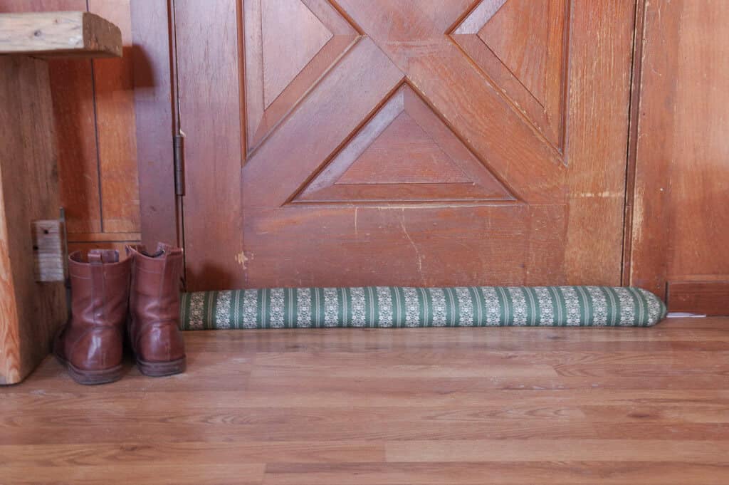 Boots and draft stopper at the base of a wooden door