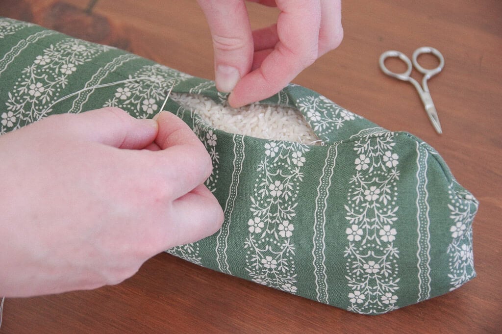 Hand holding sewing needle by fabric