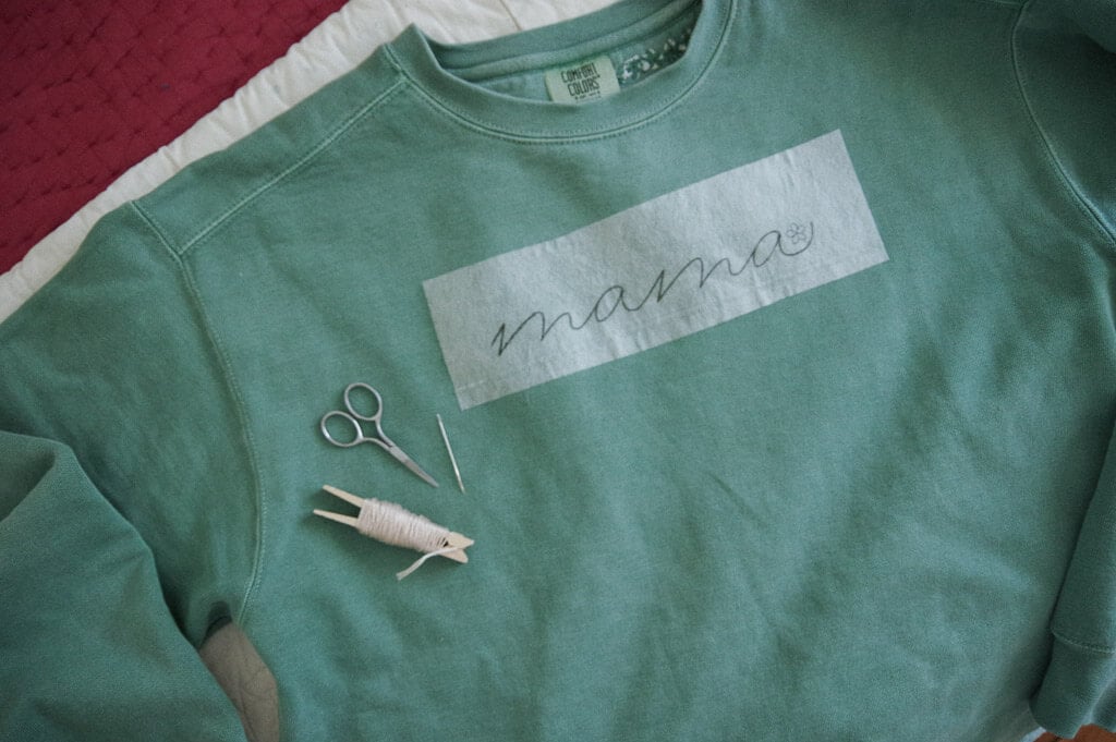 Green Sweatshirt with scissors and embroidery thread on it