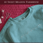 green sweatshirt on red bed with text