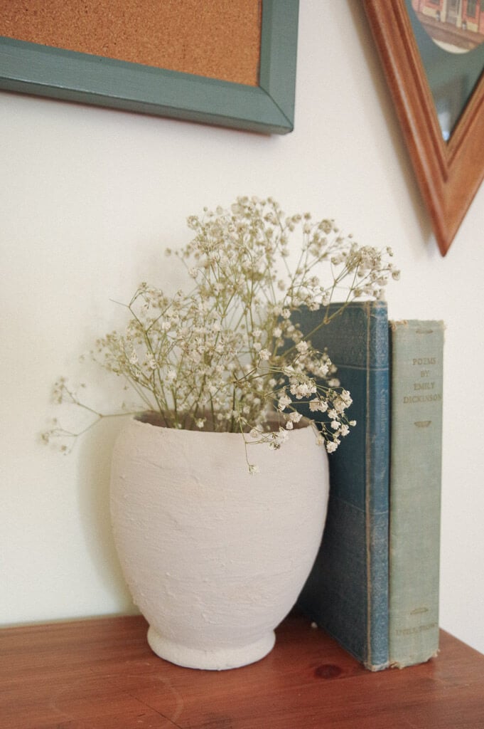 Pottery vase next to books on a wooden desk