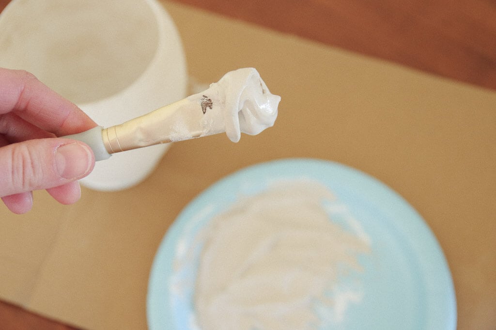 Hand holding paintbrush with goop on it