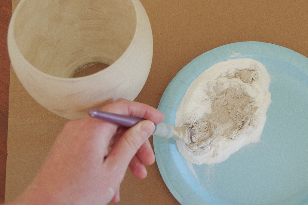 Hand mixing paint and baking soda with a paintbrush