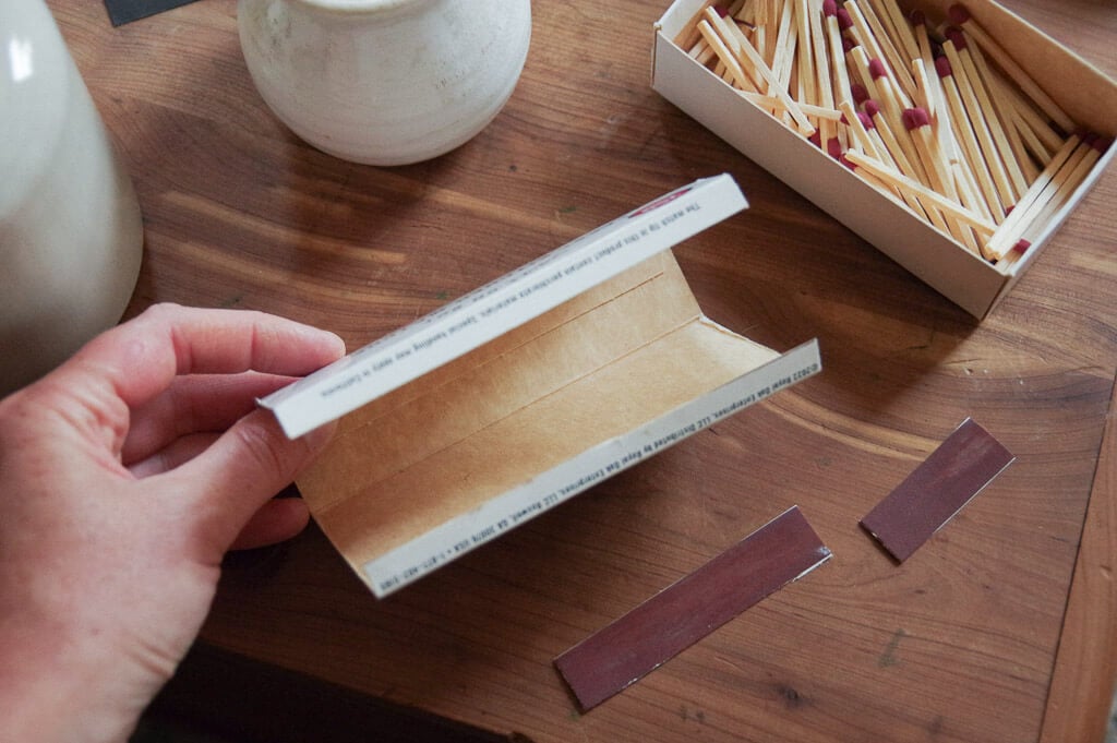 Hand holding a flap of cardboard on a table